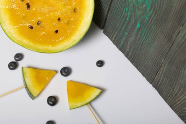 Çubuklardaki sarı karpuz parçaları. Yakınlarda yabanmersini var..