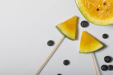 Çubuklardaki sarı karpuz parçaları. Yakınlarda yabanmersini var..