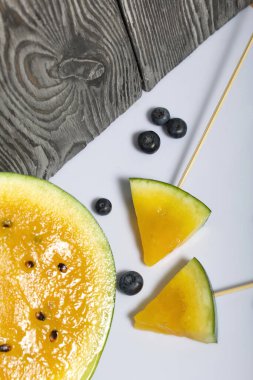 Çubuklardaki sarı karpuz parçaları. Yakınlarda yabanmersini var..