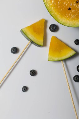 Çubuklardaki sarı karpuz parçaları. Yakınlarda yabanmersini var..