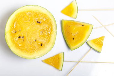 Çubuklardaki sarı karpuz parçaları. Beyaz bir yüzeyde plaka.