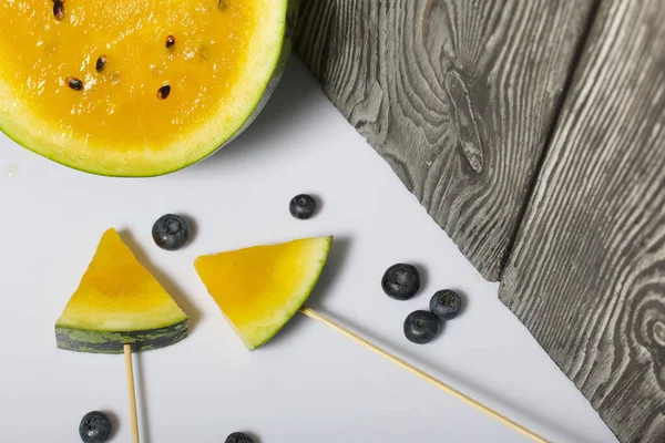 Çubuklardaki sarı karpuz parçaları. Yakınlarda yabanmersini var..