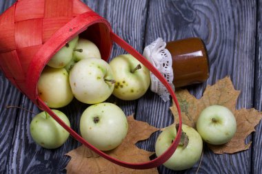Ters dönmüş elma sepeti. Yakınlarda reçel, elma ve kuru akçaağaç yaprakları var. Meyve hasadı.