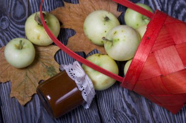 Ters dönmüş elma sepeti. Yakınlarda reçel, elma ve kuru akçaağaç yaprakları var. Meyve hasadı.