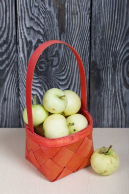 Kırmızı hasır sepetteki elmalar. Biri yakınlarda yatıyor. Meyve hasadı.