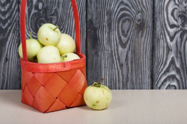 Kırmızı hasır sepetteki elmalar. Biri yakınlarda yatıyor. Meyve hasadı.