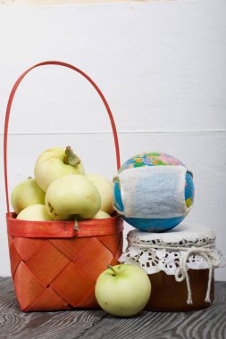 Kırmızı hasır sepetteki elmalar. Kavanozlarda reçel ve elmalar yakında. Meyve hasadı. Yakınlarda tıbbi maskeli bir küre var..