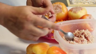 Bir adam dilimlenmiş et ve pirinçle doldurulmuş dolmalık dolma biber hazırlıyor. Biberin içine kıyma ve pirinç döker. Yakın çekim.