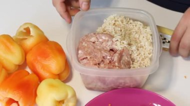 Bir adam dilimlenmiş et ve pirinçle doldurulmuş dolmalık dolma biber hazırlıyor. Kıyma ve pirinç karışımı. Yakınlarda biber var..