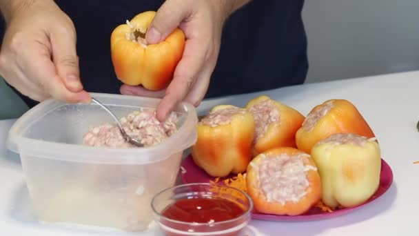 A man prepares bell peppers stuffed with minced meat and rice. Pours minced meat and rice into pepper. She puts it on a plate. — Stock Video