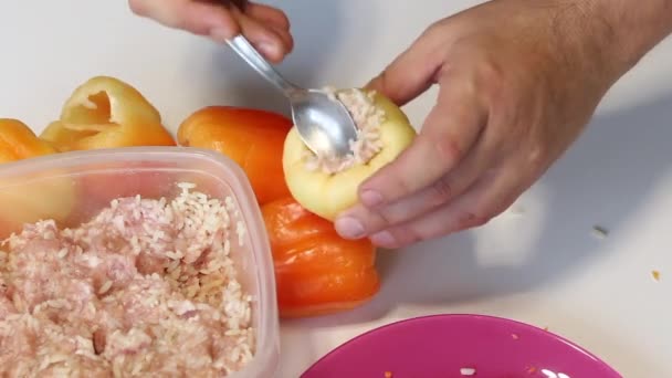 A man prepares bell peppers stuffed with minced meat and rice. Pours minced meat and rice into pepper. There is a pepper nearby. — Stock Video