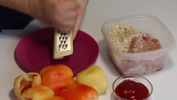 一个人在做甜椒,里面塞满了切碎的肉和米饭.在烤架上切碎胡萝卜. — 图库视频影像
