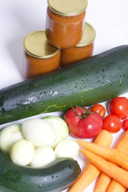 Kabak havyarı pişirmek için sebzeler. Kabak, havuç, soğan ve domatesler masanın yüzeyinde. Yakınlarda kabak havyarı kavanozları var..