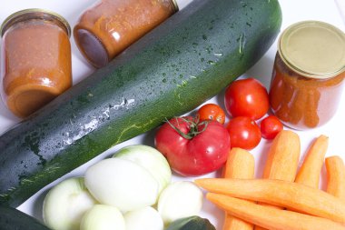 Kabak havyarı pişirmek için sebzeler. Kabak, havuç, soğan ve domatesler masanın yüzeyinde. Yakınlarda kabak havyarı kavanozları var..