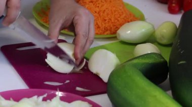 Bir adam soğan doğruyor. Kabak havyarı pişirmek için yakındaki sebzeler. Kabak, havuç, soğan ve domates...