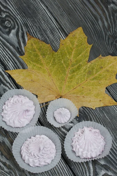 Zephyr and dried maple leaves. On painted pine planks.