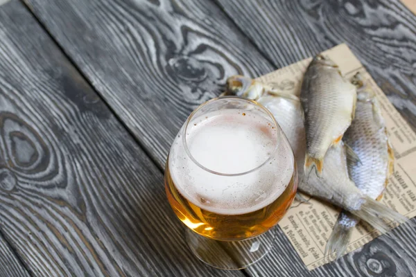 A glass of beer. Dried river fish lies nearby.