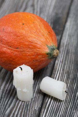 Turuncu balkabağı ve mum koçanları. Çam ağacından yapılmış tahtalarda siyah beyaz boyanmış..