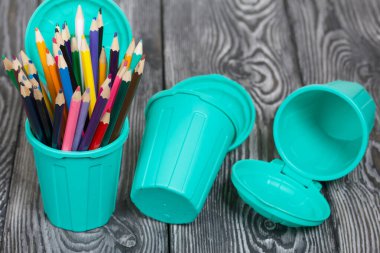 Kalem tutacağındaki renkli kalemler. Çöp konteynırı şeklinde kalemler. Çam ağacından yapılmış tahtalarda siyah beyaz boyanmış..