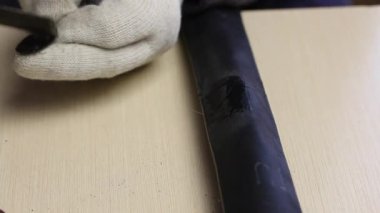 Bir adam bisiklet tüpündeki delik yerine yapıştırıcı sürmüş lastik bir yama uygular. Parmaklarıyla sıkıca bastırıyor. Yakın çekim..