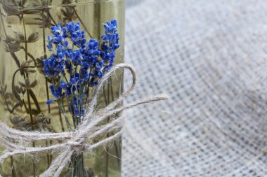 Bir şişe lavanta tentürü. Şişeye bir demet lavanta bağlanmış. Kaba ketenler üzerinde. Yakın çekim..