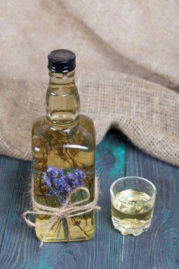 Bir şişe lavantalı votka. Şişeye bir demet lavanta bağlanmış. Yakınlarda bir bardak içki var. Alabildiğine yemyeşildirler..