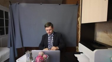 Video görüşmesi sırasında yemek yemek. Takım elbiseli bir adam video iletişimiyle konuşuyor. İletişim kurarken el kol hareketi yapıyor. Tepsinin yanında kahve makinası var..