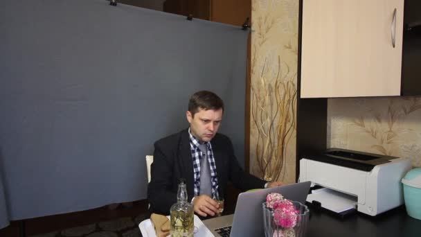 Eating during a video call. A man in a business suit is talking via video communication. He drinks a glass of alcohol and eats from a plate. — Stock Video