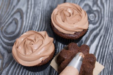 Krem peynirli çikolatalı kekler. Yanında süsleme için kremalı bir pasta torbası var..