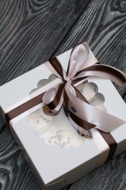 Bardakta Zephyr. Bisküvi ve çikolatalı. Kurdeleyle bağlanmış bir hediye kutusuna yerleştirilmiş. Siyah beyaza boyanmış çam ağaçlarında.