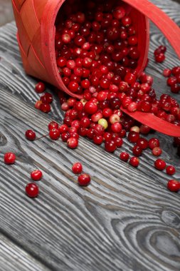 Ters dönmüş bir sepet kızılcık. Böğürtlenler ahşap bir yapı ile kalasların yüzeyine saçılmıştı..