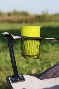 Kamp sandalyesi parçası. Tribünde plastik bir cam var. Arka plan bulanık. Sonbahar pikniği.