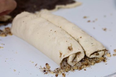 Bir kadın rulo hamuru ceviz katmanıyla yuvarlıyor. Çörek pişiriyorum..