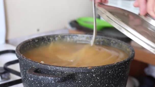 男はアップルジャムを作っている。鍋にスプーンでそれを攪拌.クローズアップショット. — ストック動画