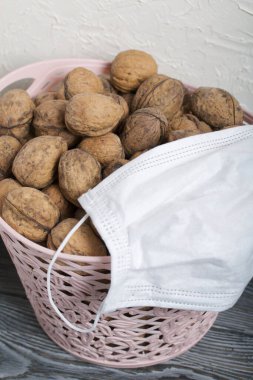 Cevizli bir sepet. O bir tıbbi maske takıyor. Yakınlarda beyaz bir tahta kutu var..