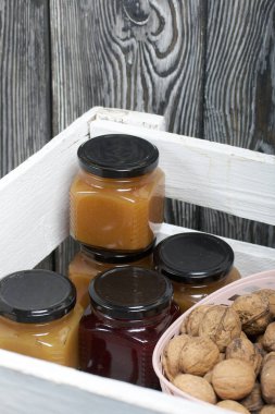 Cevizli bir sepet. Reçel kavanozları. Beyaz tahta bir kutunun içinde dur..