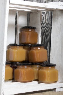 Kavanozda meyve reçeli. Beyaza boyanmış ahşap bir kutunun içinde duruyor..