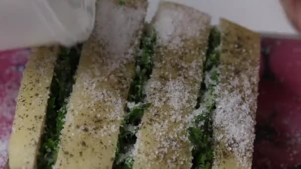 A piece of bacon, cut into an accordion. Filled with parsley and adjika. The woman sprinkles it with salt and pepper. Salted lard with herbs and spices. Close-up. — Stock Footage A piece of bacon, cut into an accordion. Filled with parsley and adjika. The woman sprinkles it with salt and pepper. Salted lard with herbs and spices. Close-up. Stock Footage
