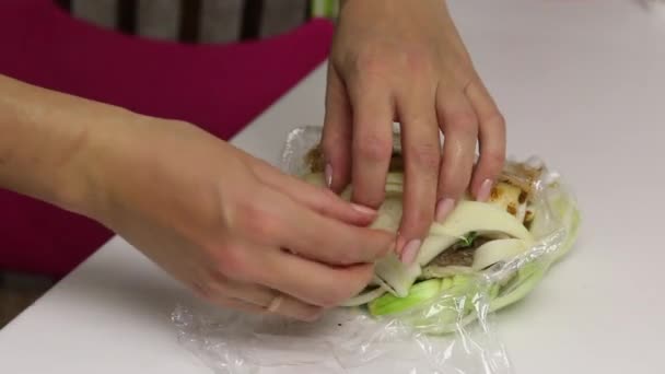 Un pedazo de tocino, cortado en un acordeón. Lleno de perejil y adjika. La mujer lo pone en cebolla picada y lo envuelve en una envoltura de plástico. Manteca salada con hierbas y especias — Vídeos de Stock