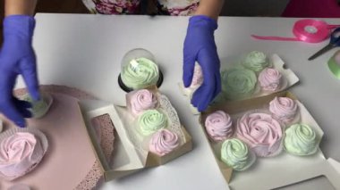 Bir kadın hediye karton kutulara pembe ve açık yeşil zephyr serer..