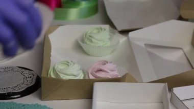 Bir kadın hediye kutusunda açık yeşil ve pembe şekerlemeler taşıyor. Paketleme için yakın aksesuarlar.