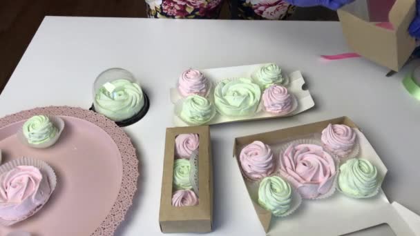 Una donna confeziona marshmallow rosa e verde chiaro in scatole di cartone regalo. — Video Stock