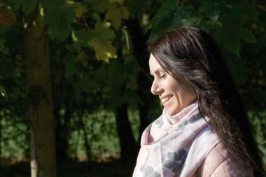 Sonbahar parkında yürüyüş yapan bir kız. Sarı yapraklarla cadde boyunca yürüyorum. Yüzü çok yakın..