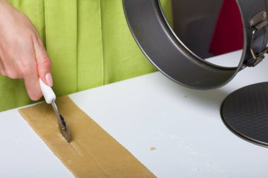 Kadın hamuru kesiyor. Yemek aletleri yakınlarda. Levington keki, hazırlık aşamaları..