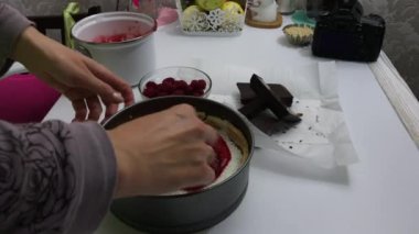 Bir kadın hindistancevizinin üzerine ahududu reçeli döküyor. Fırında pişmiş sünger kekinin içinde. Levington Turtası Pişirme