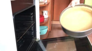 Kadın hamuru fırına katlanabilir bir kek tepsisine koyar. Levington Turtası Pişirme.