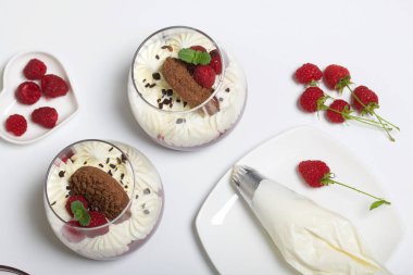 Ahududu reçelli krem peynirli tatlı pişirmek. Malzemeler masa yüzeyine serildi. Kurabiye, ahududu ve nane ile süslenmiş..