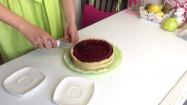 Kadının biri ahududu jölesiyle Levington pastası kesiyor. Ahududu ile süslenmiş..