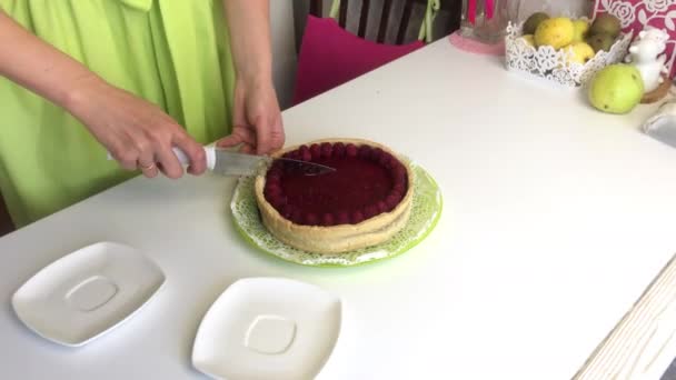 Een vrouw snijdt een Levington cake met frambozengelei. gegarneerd met frambozen. — Stockvideo