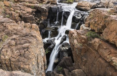 2 kahverengi kayanın arasında uzun bir şelale var.